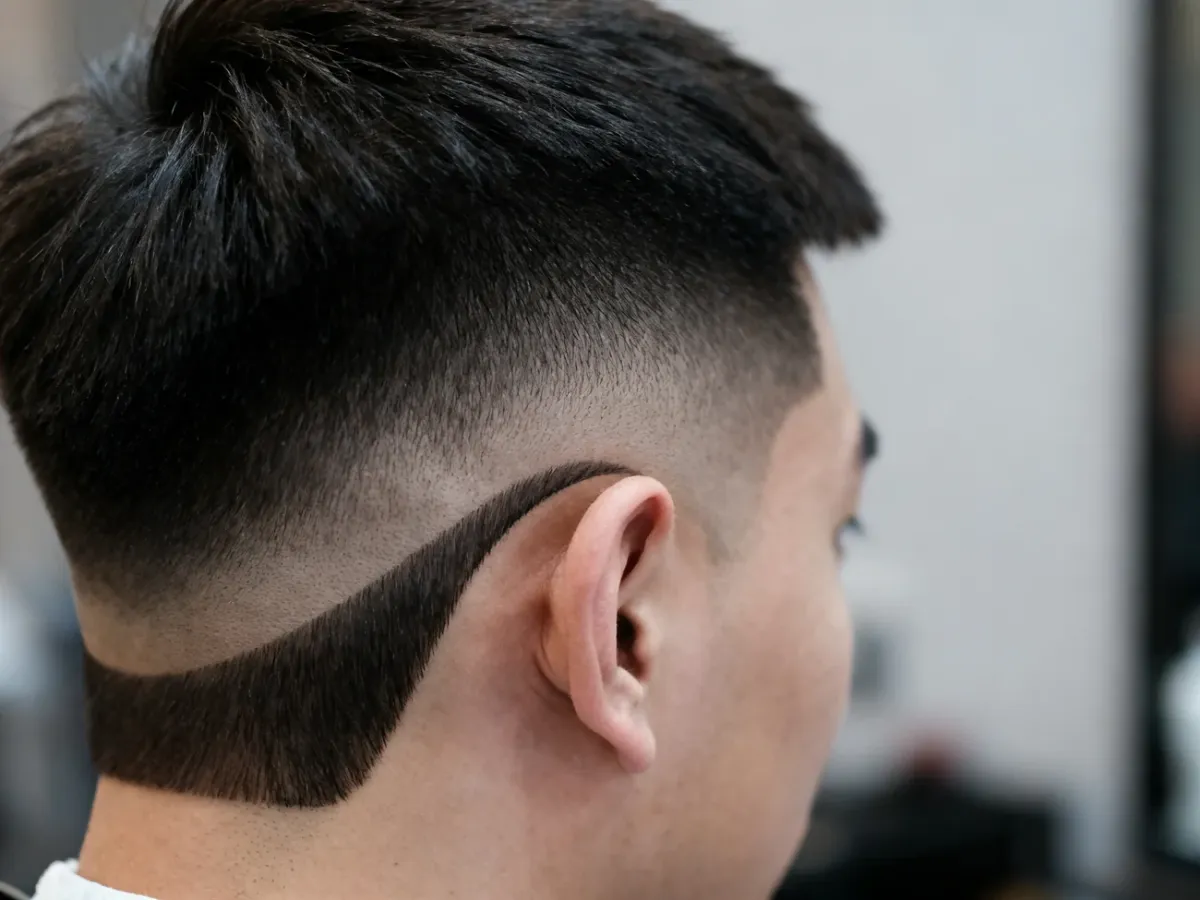 Profil fryzury low drop fade z łukowatą linią cieniowania za uchem