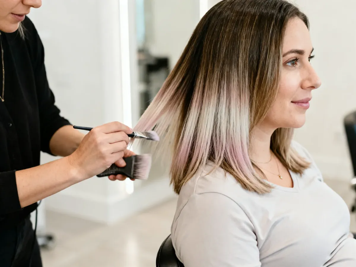 Ciężarna kobieta podczas delikatnego balayage w jasnym salonie fryzjerskim